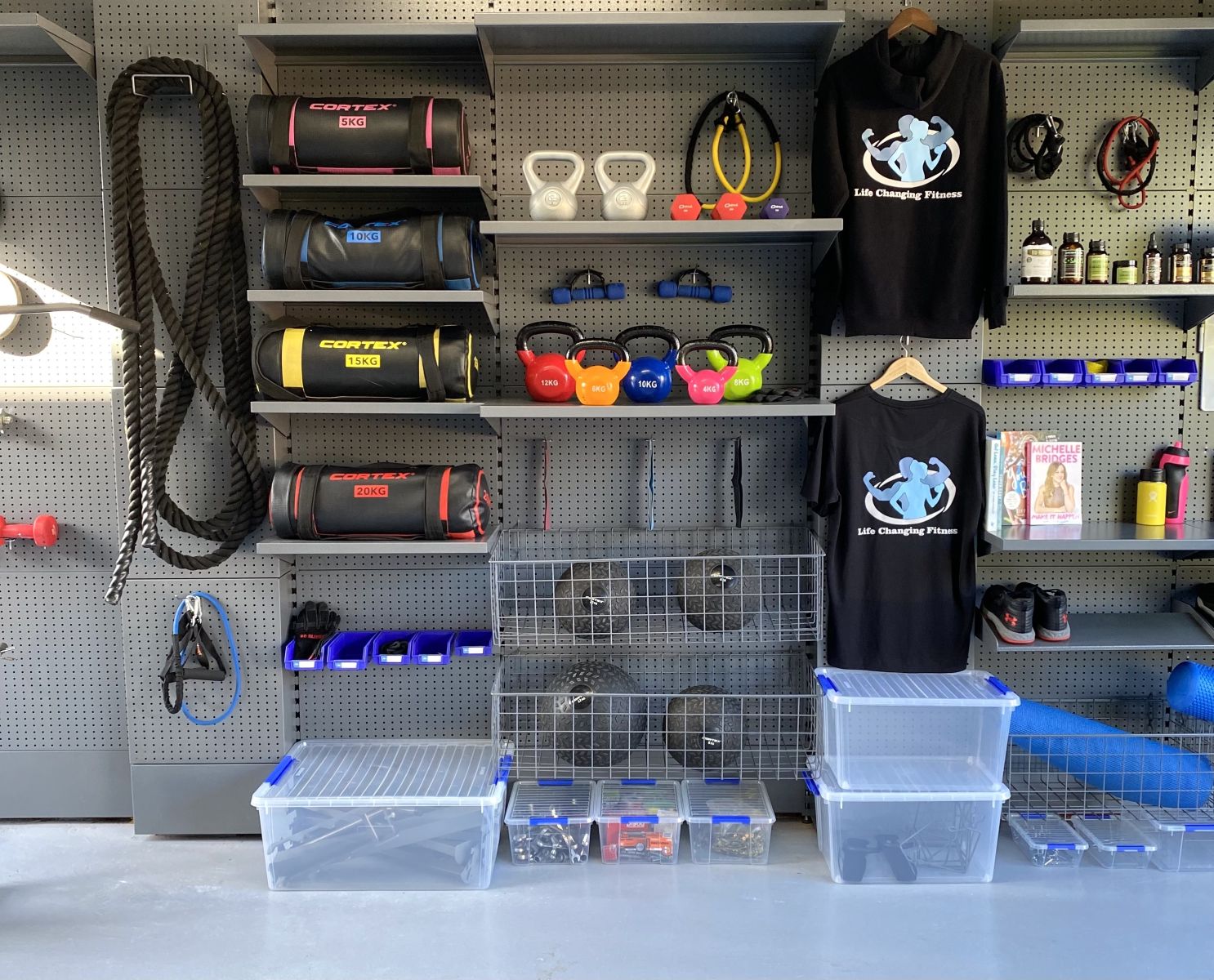 A garage storage system designed by GarageKing for a home gym set up with shelves, hooks, baskets and holders containing gym equipment