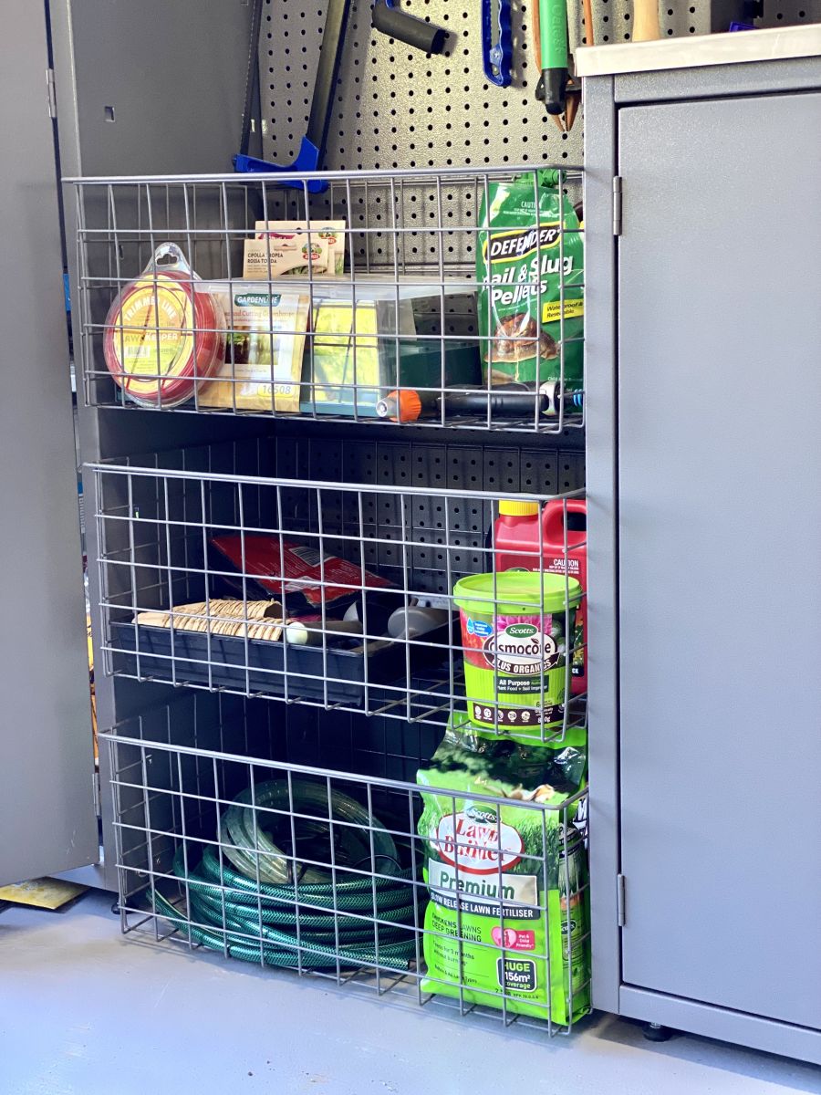 Three garage storage baskets containing gardening products