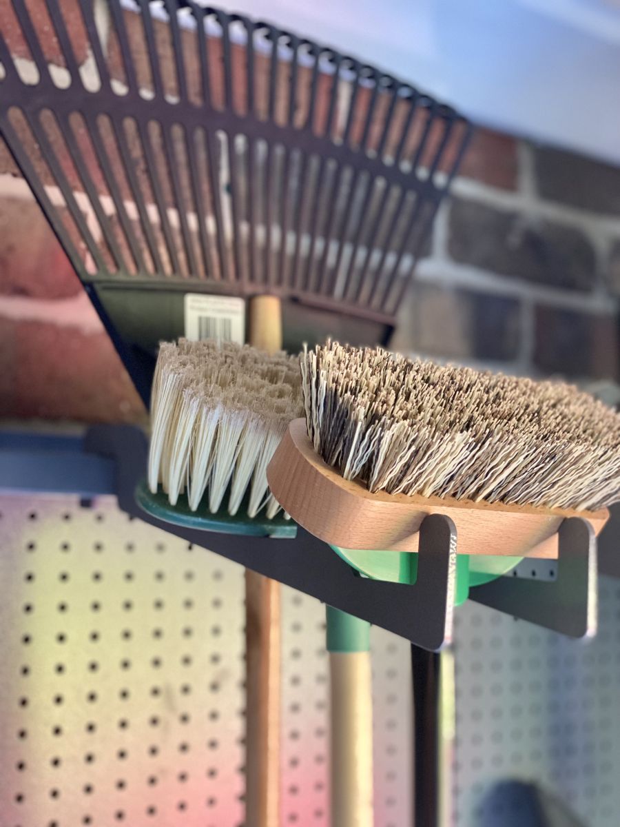 A garage storage holder for rakes and brooms