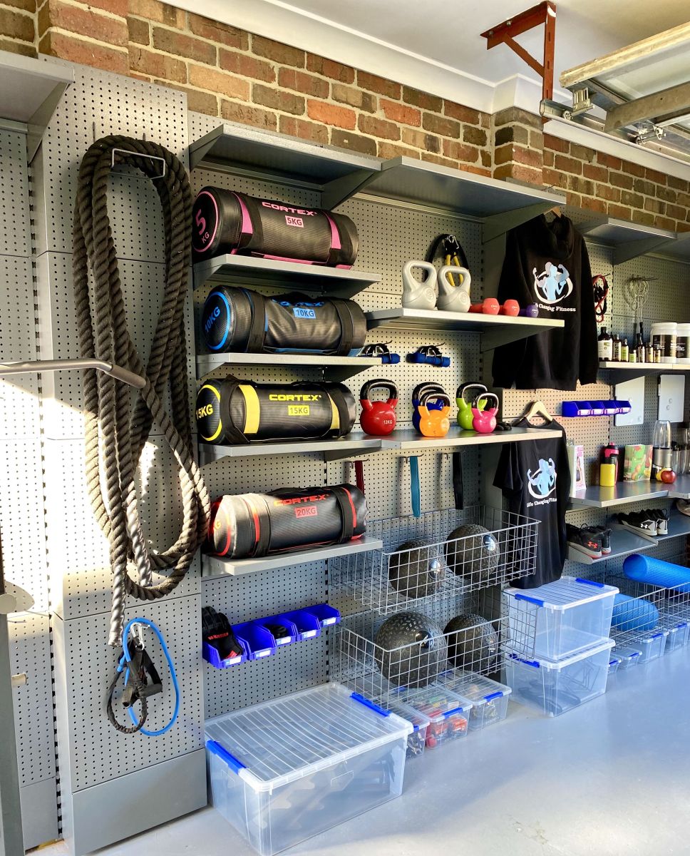 A Melbourne home gym set up in a garage with weights, ropes, weight bench, workout gear and other gym accessories