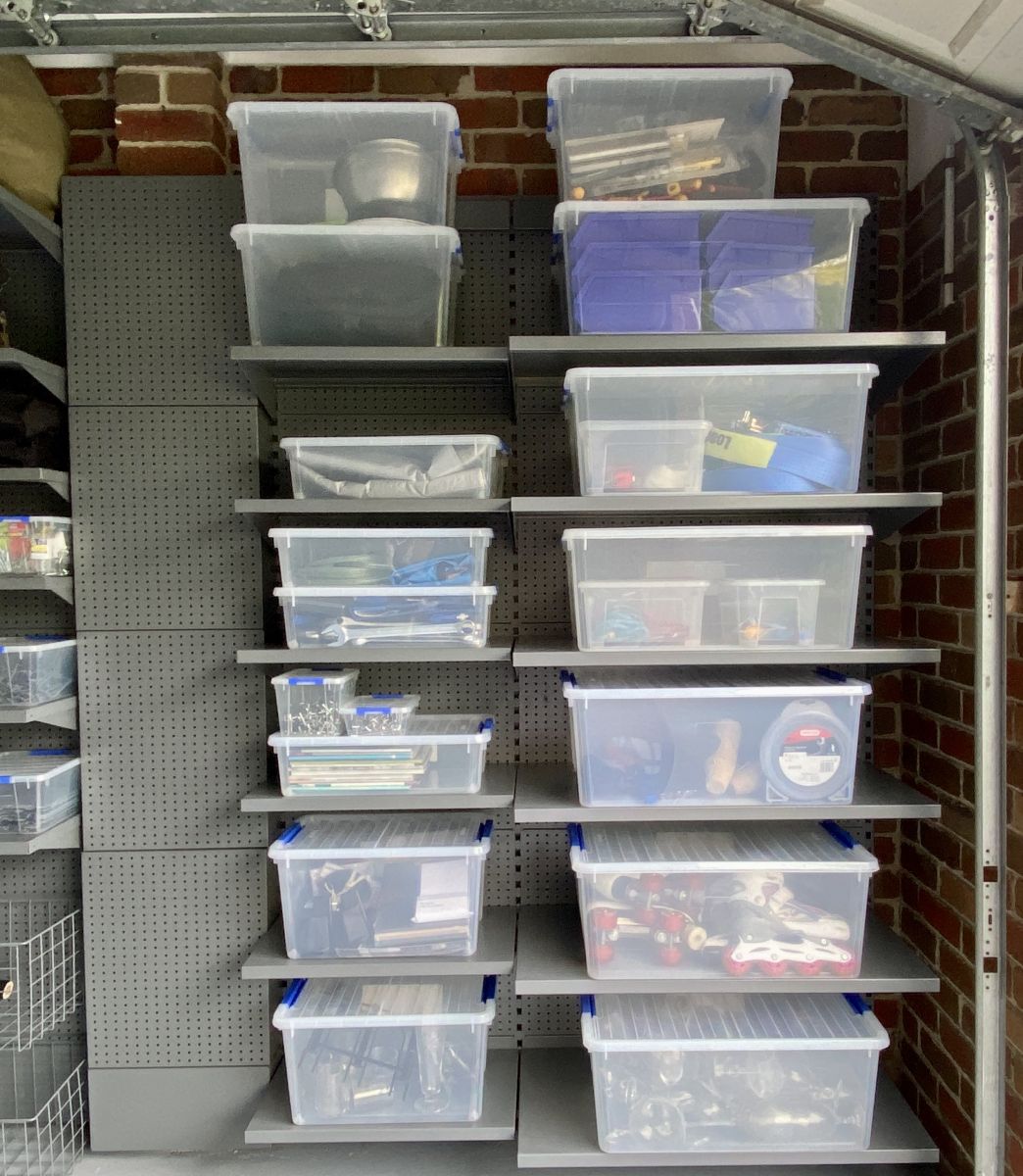 A garage storage shelving system with clear plastic tubs for storage