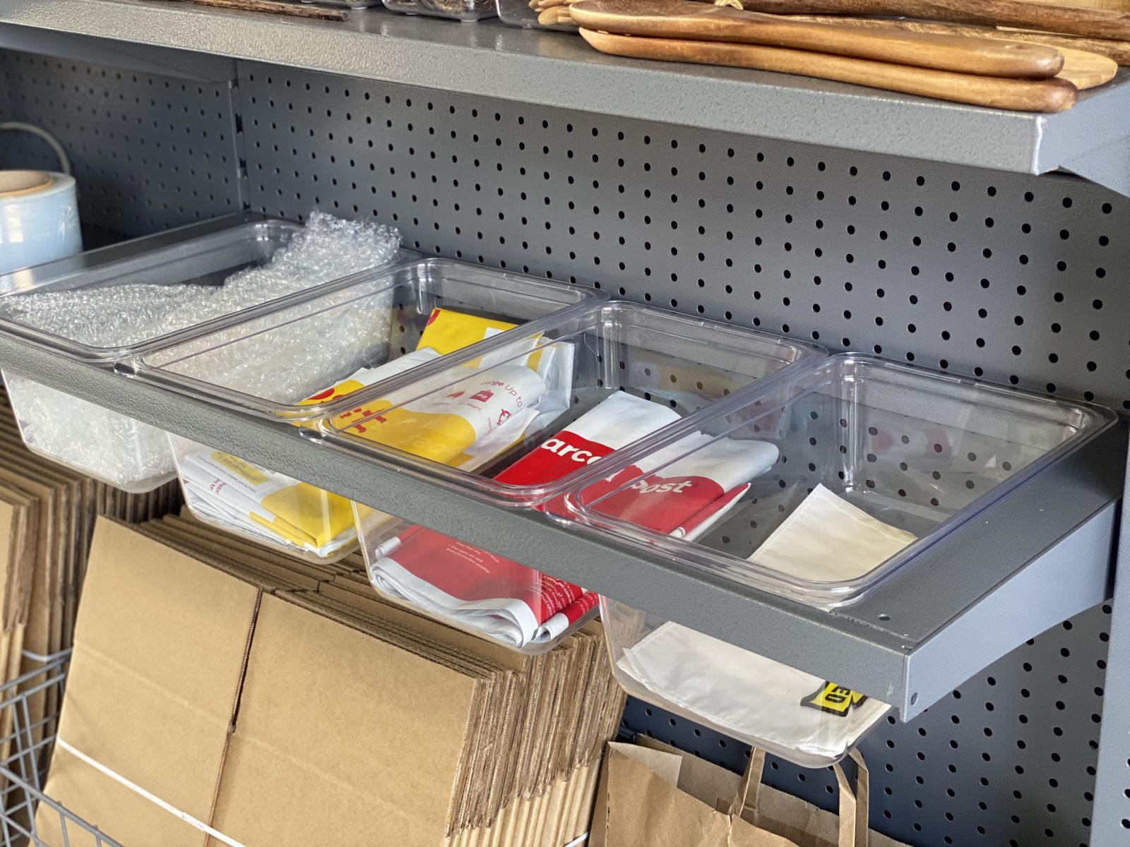 A garage storage shroud with plastic storage tubs with postage bags and materials