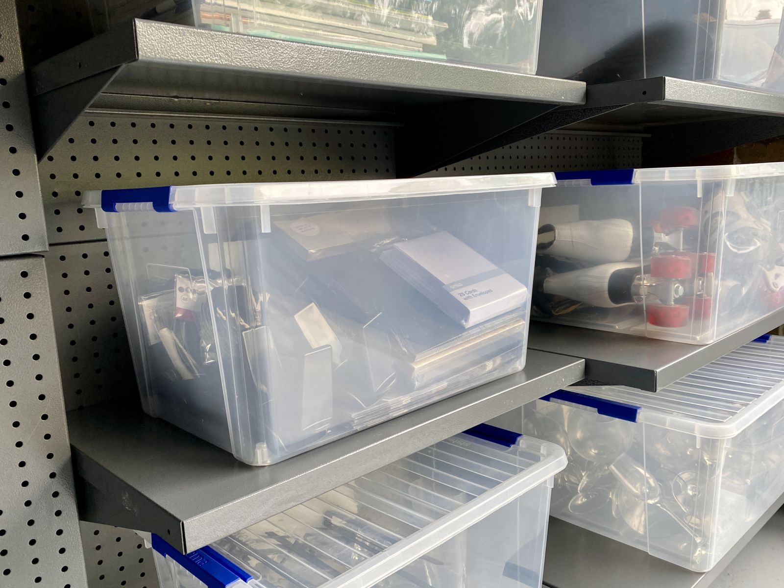 grey metal garage storage system with perforated wall bays, adjustable shelving and system plastic storage tubs