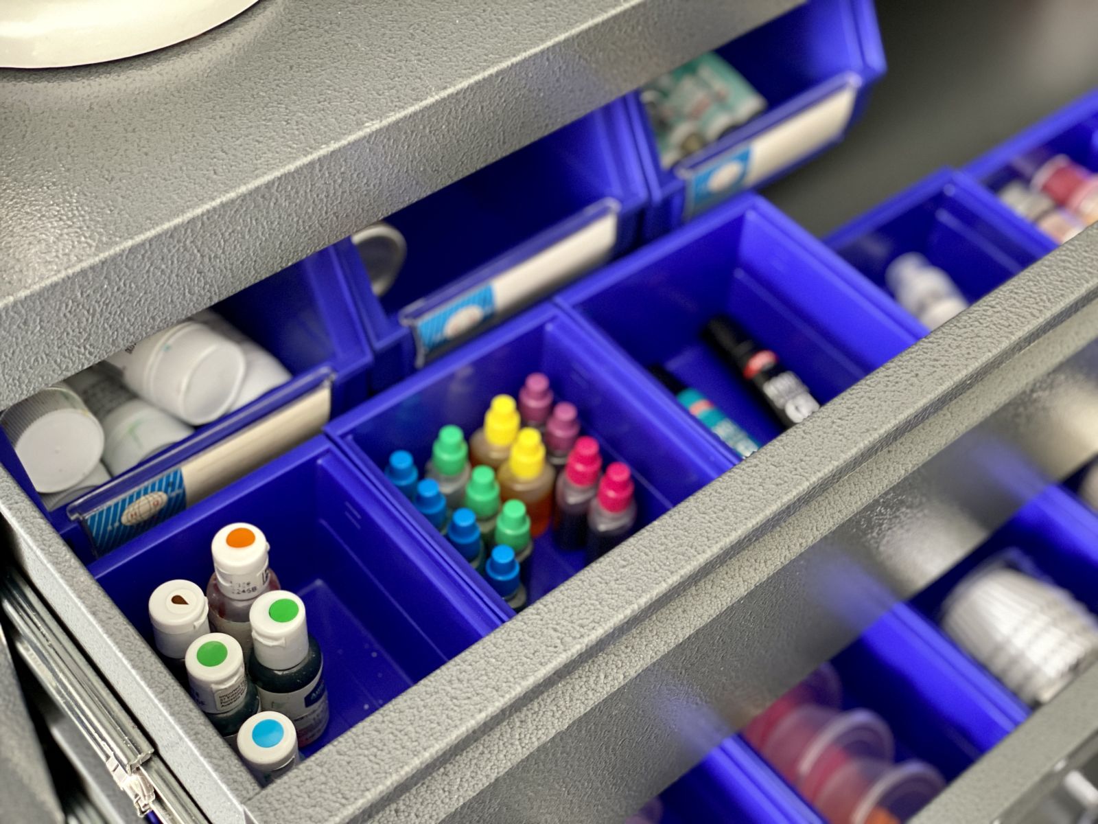 Blue plastic tubs in a metal garage drawer